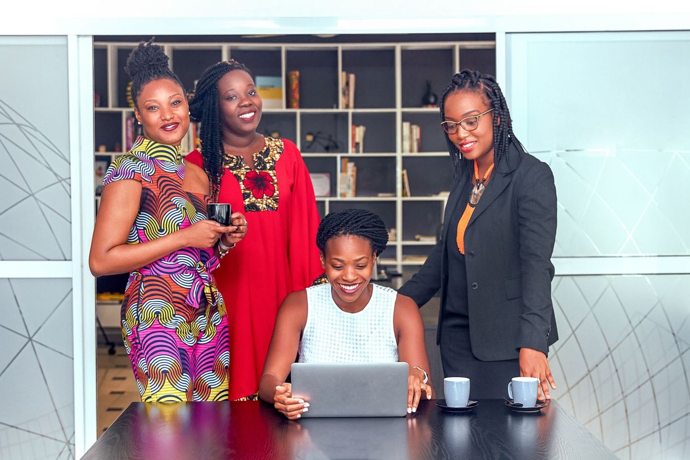 Four women looking at a laptop together in an office